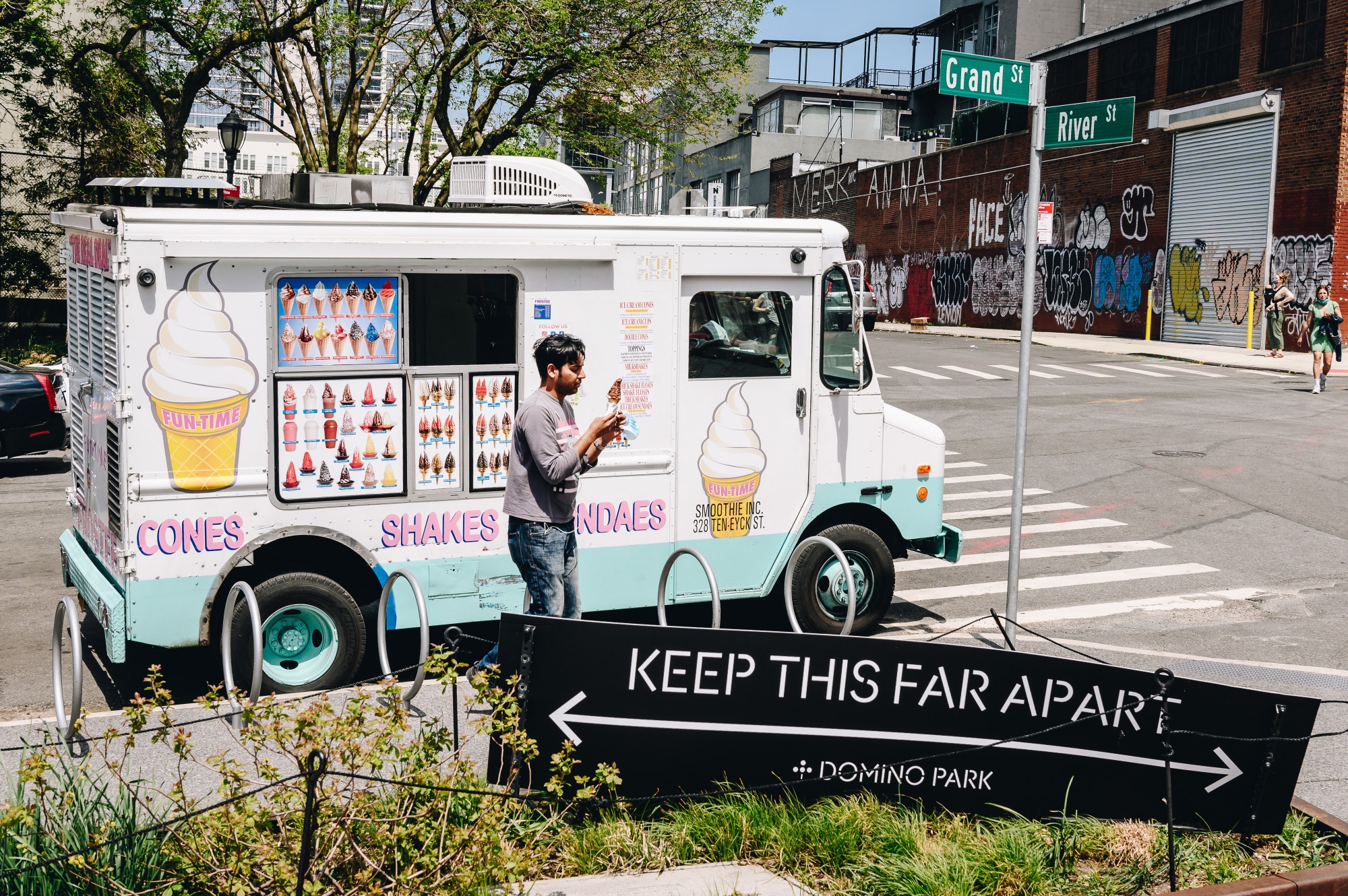 A person purchases an ice cream cone from a food truck at Domino Park in the Brooklyn Borough of New York, U.S., on Friday, May 15, 2020. Mayor Bill de Blasio says the city along with the NYPD will be launching a pilot program in public parks this weekend to monitor crowds and ensure people are practicing social distancing.