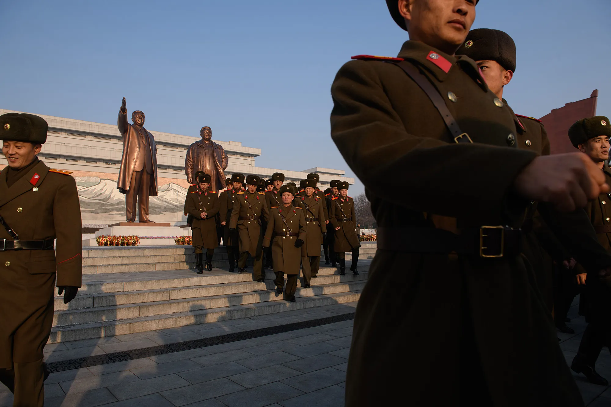 Korean People's Army soldiers walk before statues of late North Korean leaders Kim Il Sung and Kim Jong Il in Pyongyang.