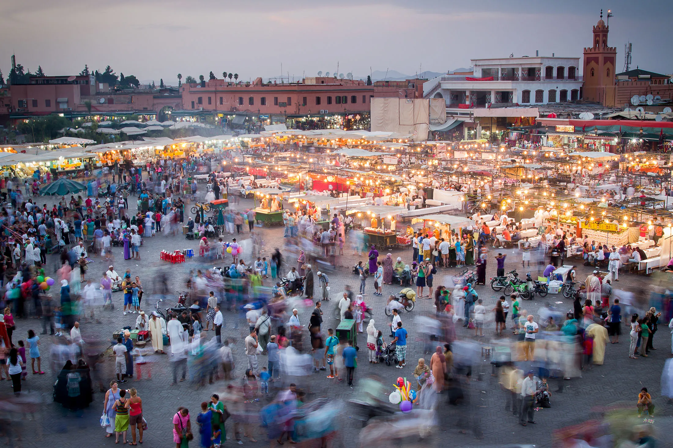 A long exposure across the square of Jamaa el Fna in Marrakesh.The bustling square is full of people wondering on foot, experiencing the unique atmosphere, sights &amp; smells.Further into the image on the right is the smoke &amp; lights from the largest open air restaurant in the world.
