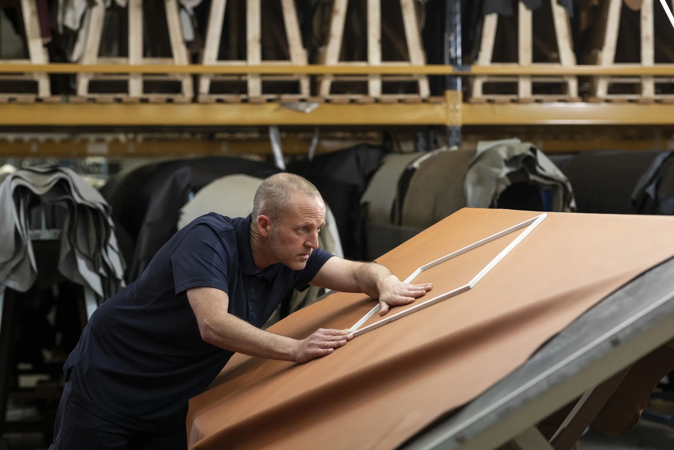 Alister MacDonald inspects leather, using an instrument that helps highlight&nbsp;the panel sizes when cuts are due.