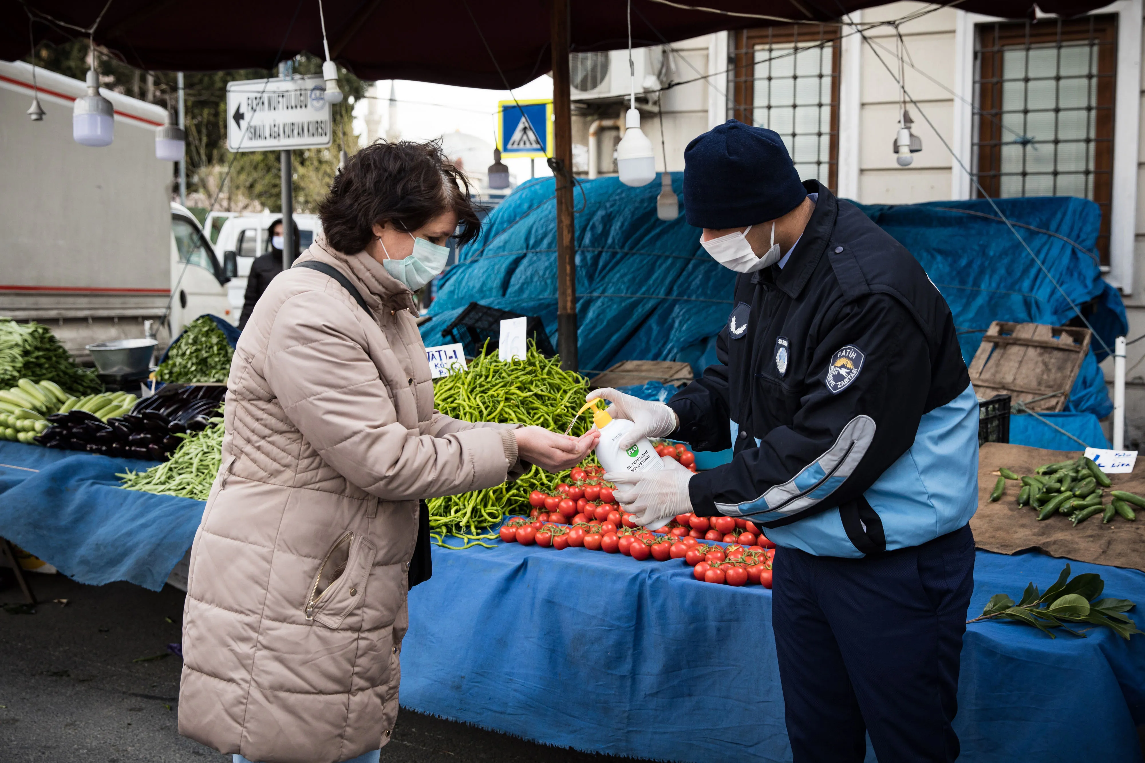 A shopper receives sanitizer hand gel from a municipal worker before shopping at the Fatih outdoor food market in Istanbul, Turkey.