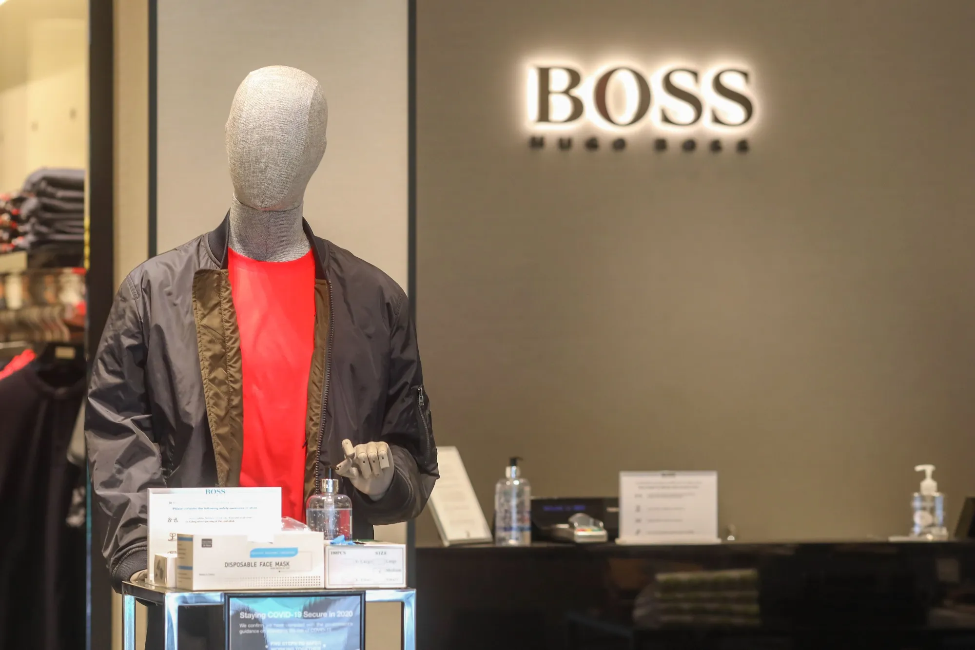 A mannequin stands next to a sanitizing station inside a Hugo Boss AG clothing store in London.