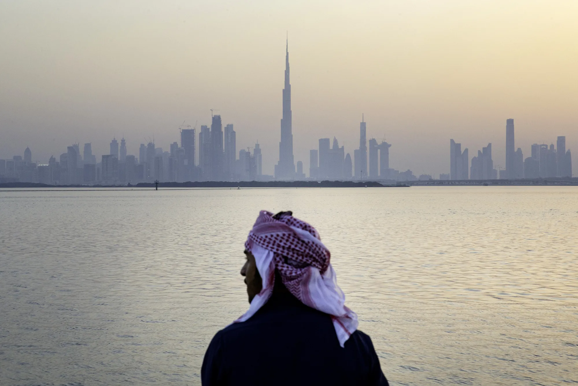 A man looks out from the Dubai Creek Habour Development towards the Burj Khalifa tower in Dubai.