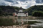 A visitor walks along exposed rock on the shoreline of the River Rhine near Pfalzgrafenstein castle in Kaub, Germany.