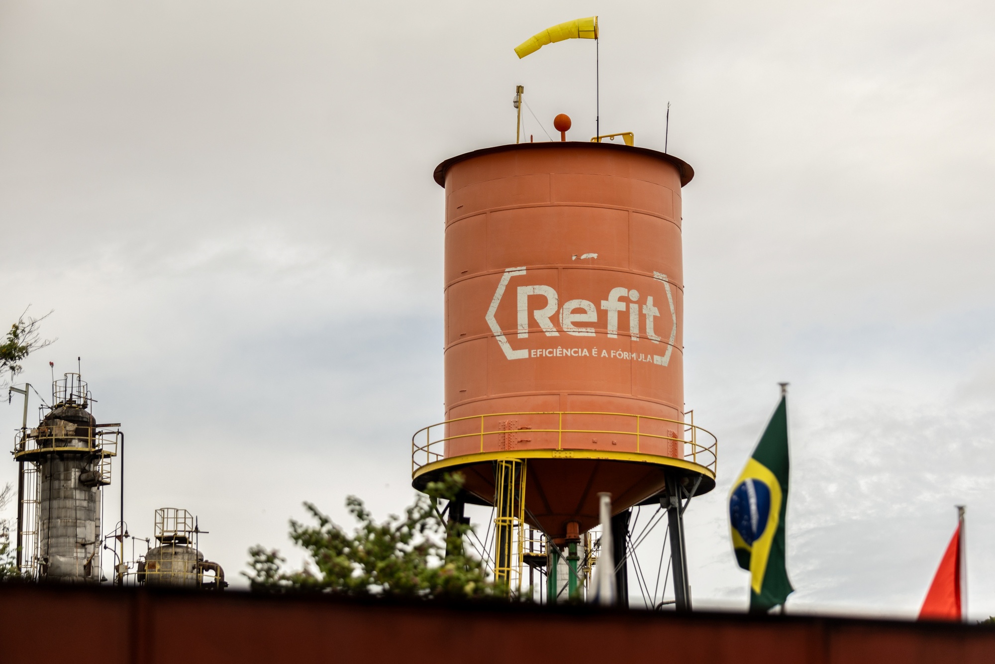 Signage on a water tank at the Refinaria de Petroleos de Manguinhos in Rio de Janeiro, Brazil, on Wednesday, Dec. 10, 2025. Investigations show that Grupo Refit, the conglomerate that controls the major refinery, moved more than 70 billion reais ($12.9 billion) in one year using its own companies, investment funds and offshore entities to conceal and shield profits, according to Brazil's tax service.