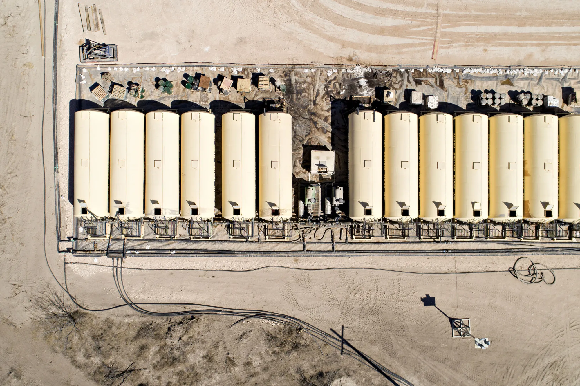 Tanks containing drilling fluid sit in a row near a&nbsp;rig drilling in the Permian Basin near Midland, Texas.