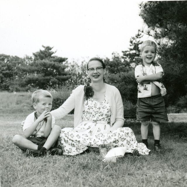 Ken with his mother, Lyla Burns, and his brother sit on a lawn together.