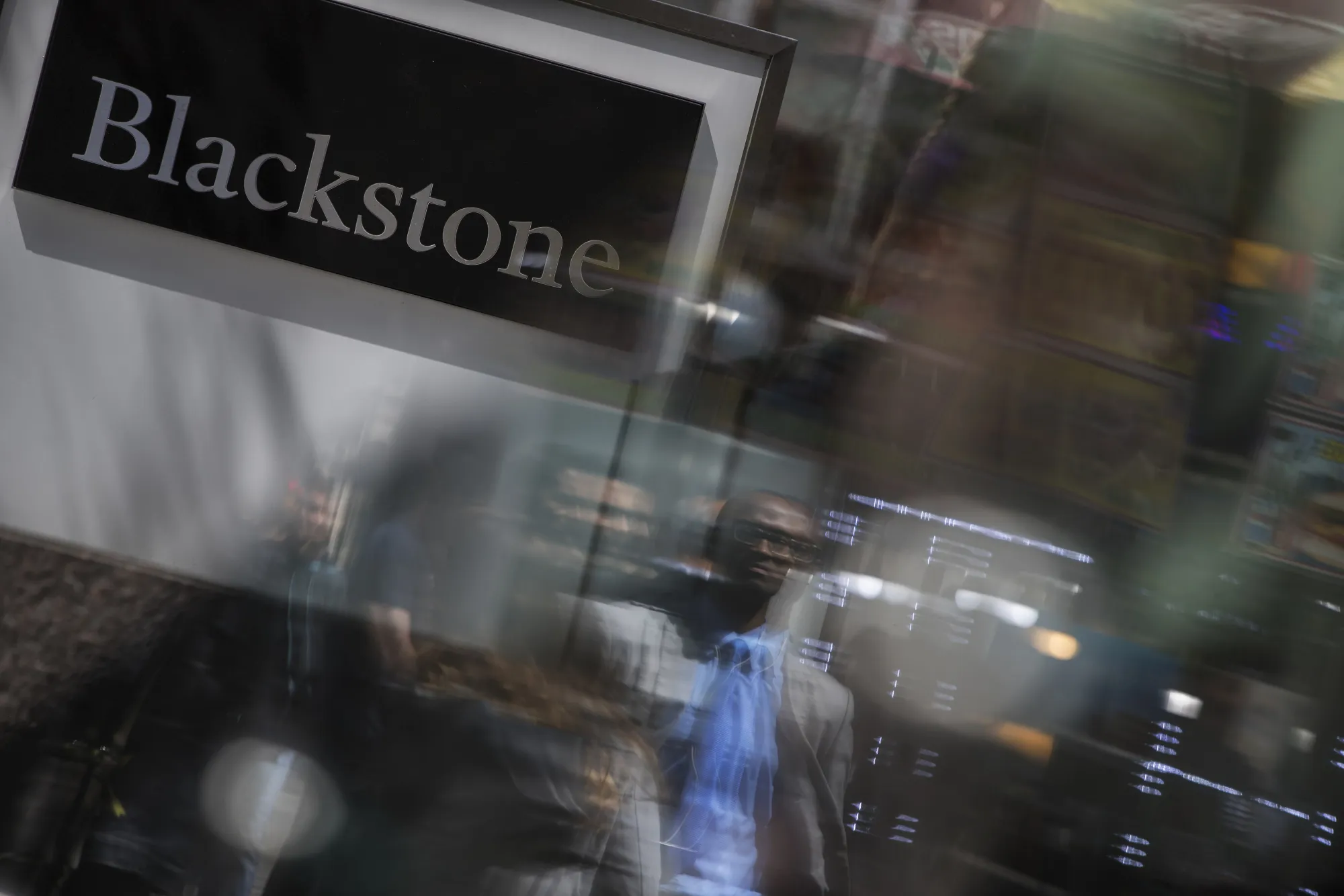Pedestrians are reflected on glass in front of Blackstone Group LP headquarters in New York.
