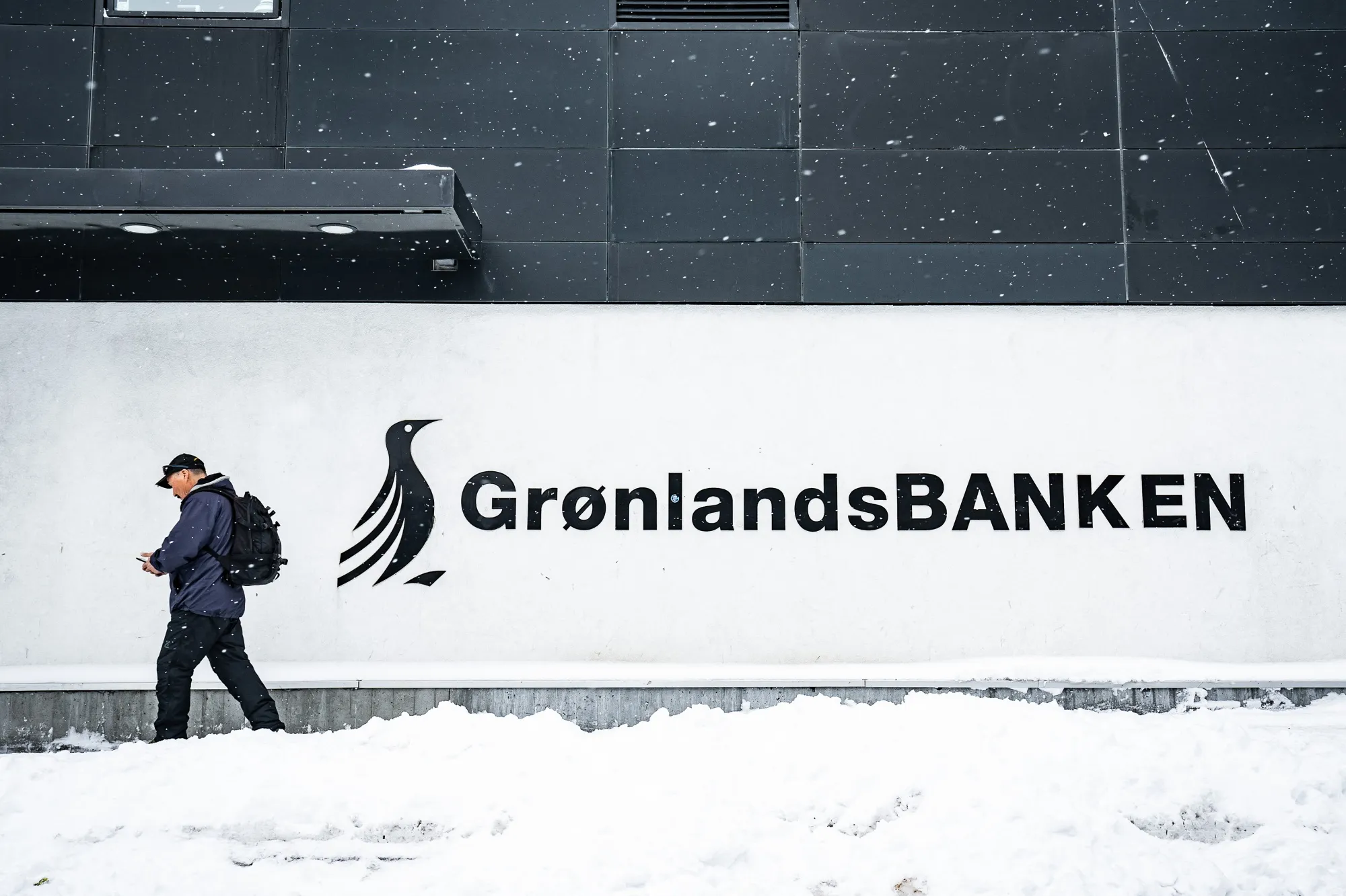 A man walks past a sign for the Bank of Greenland&nbsp;in Nuuk, Greenland.