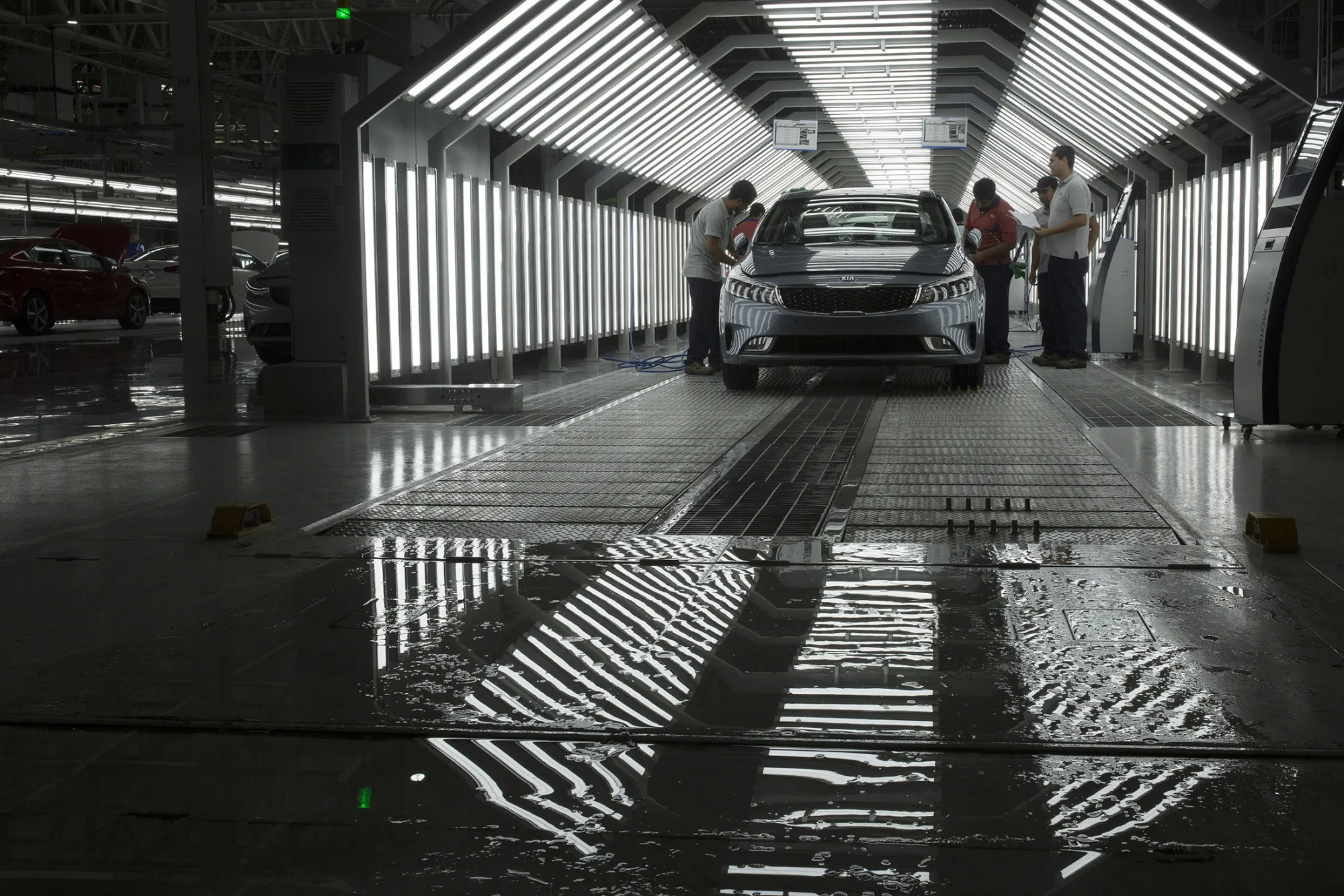 Workers inspect a vehicle after a rain test at the Kia Motor Corp. assembly plant in Pesqueria, Mexico.
