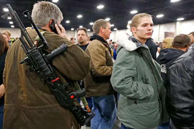 A man carries a semiautomatic assault rifle he is trying to sell at the Rocky Mountain Gun Show in Sandy, Utah, on Jan. 5