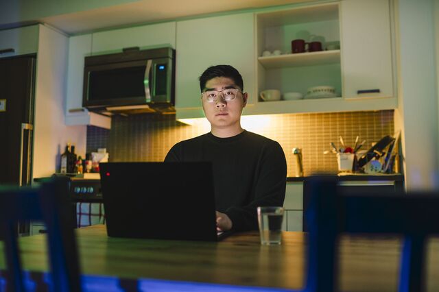 Anthony Tan photographed in his shared kitchen with his laptop. 