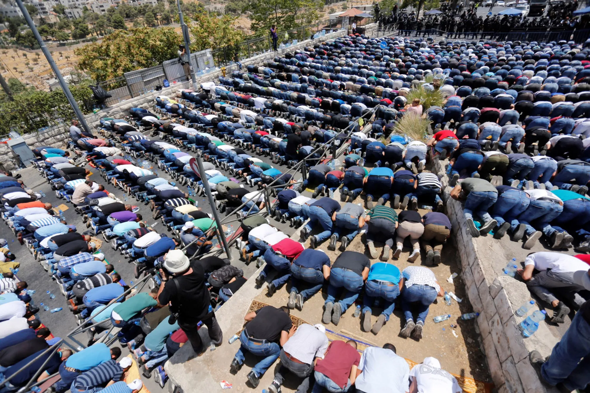 Israeli security forces stand guard as Palestinian Muslims perform Friday Prayer at Valley of the Walnuts area in Jerusalem on July 28, 2017.
