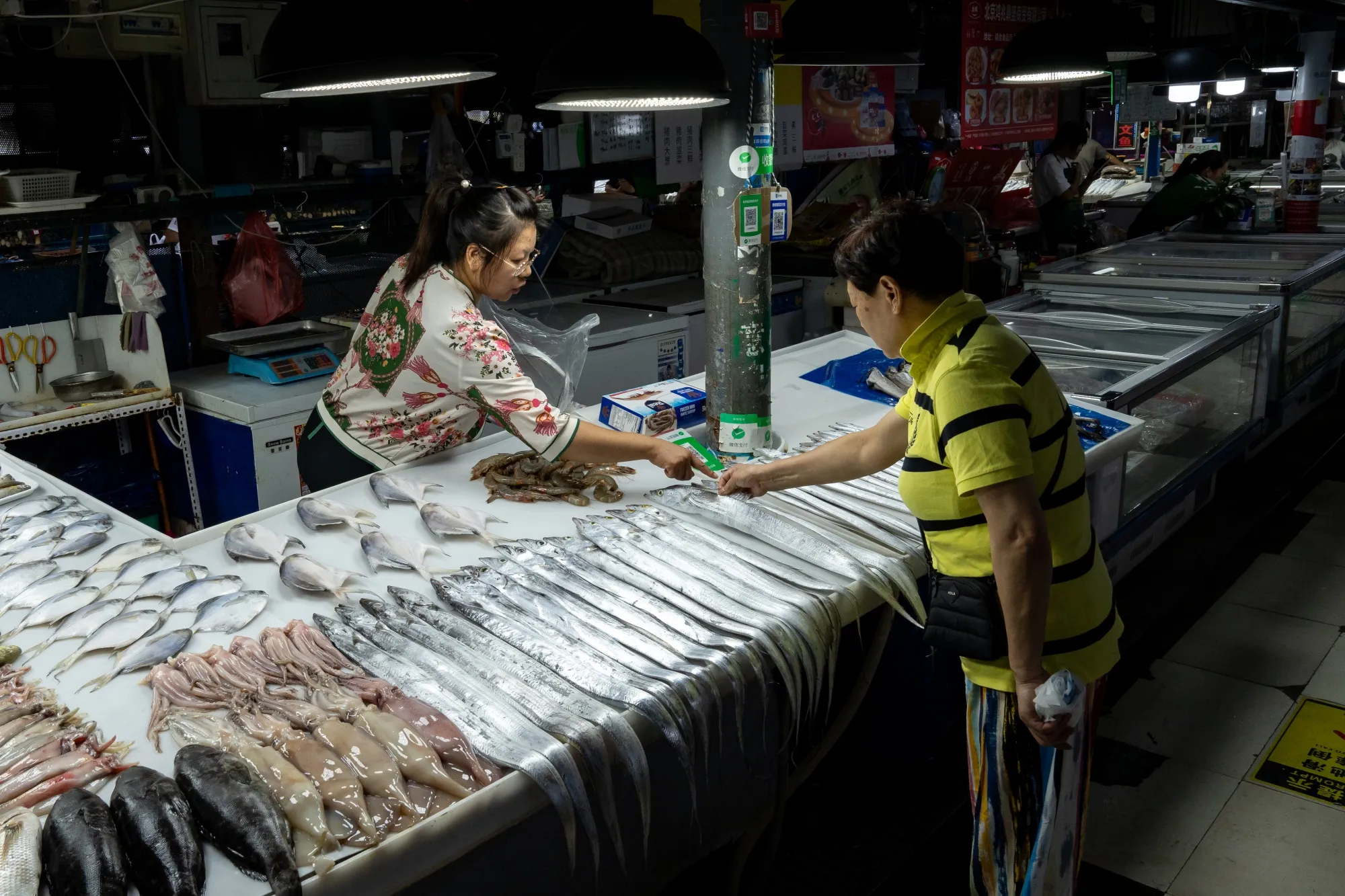 A customer selects fish at a seafood market in Beijing.
