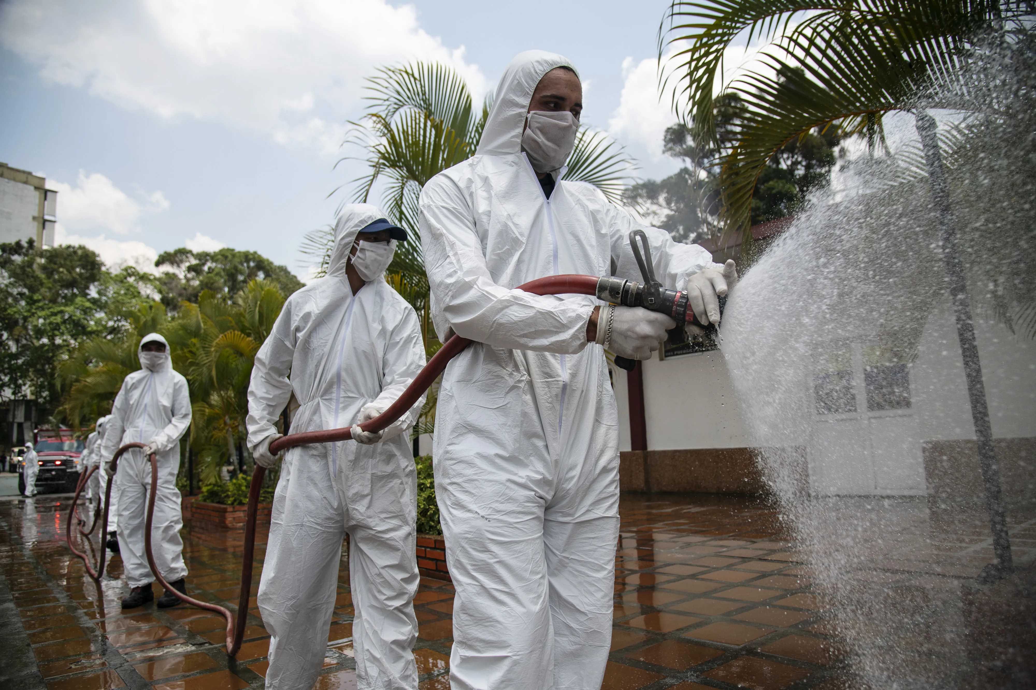 Members of the Caracas fire department wearing protective gear spray water and disinfectant over the Bolivarian National Guard (GNB) headquarters in the Mariperez neighborhood of Caracas.