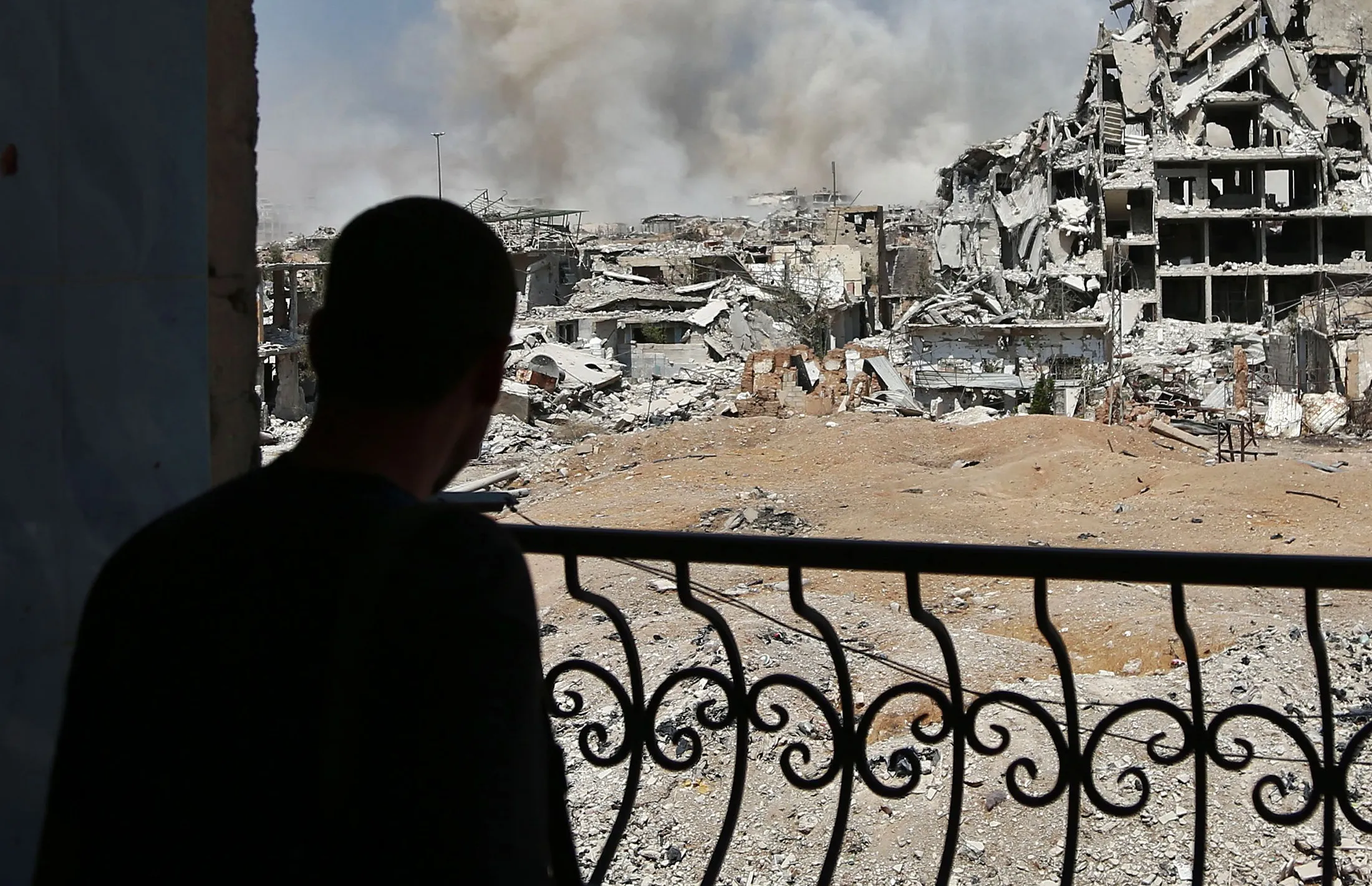 A man looks at smoke rising from buildings following a strike in the Jobar district, east of the Syrian capital on Sept. 14, 2017.
