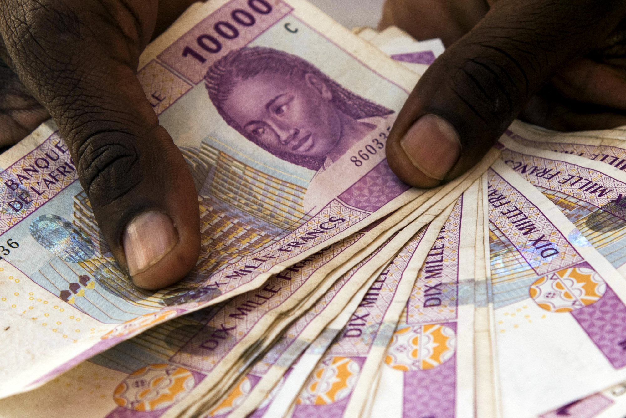 A man displays 10,000 denomination Central African franc banknotes in this arranged photograph in N'Djamena, Chad. Photographer: Xaume Olleros/Bloomberg