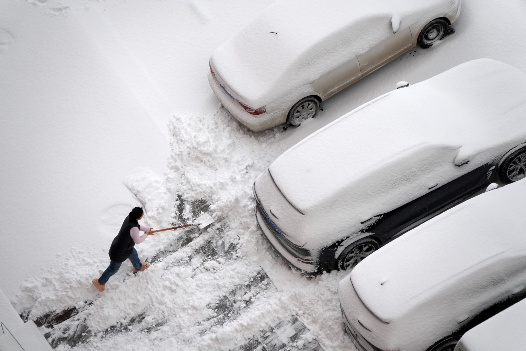 A citizen sweeps snow on the street in Yantai, Shandong Province, China, on January 11, 2026. (Photo by Costfoto/NurPhoto via Getty Images)