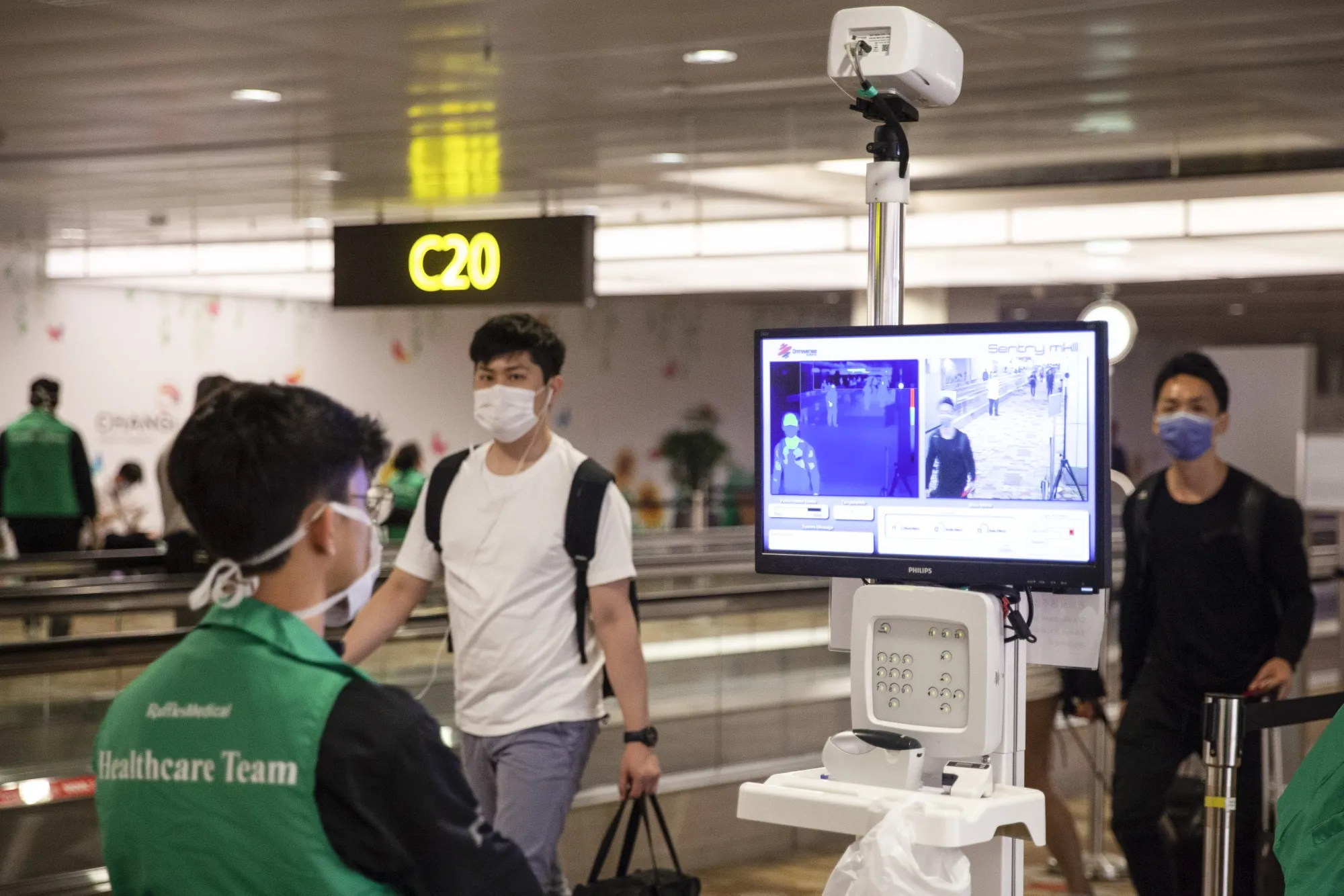 Helath officials monitor the temperatures of travelers at Changi Airport in Singapore, on March 11.