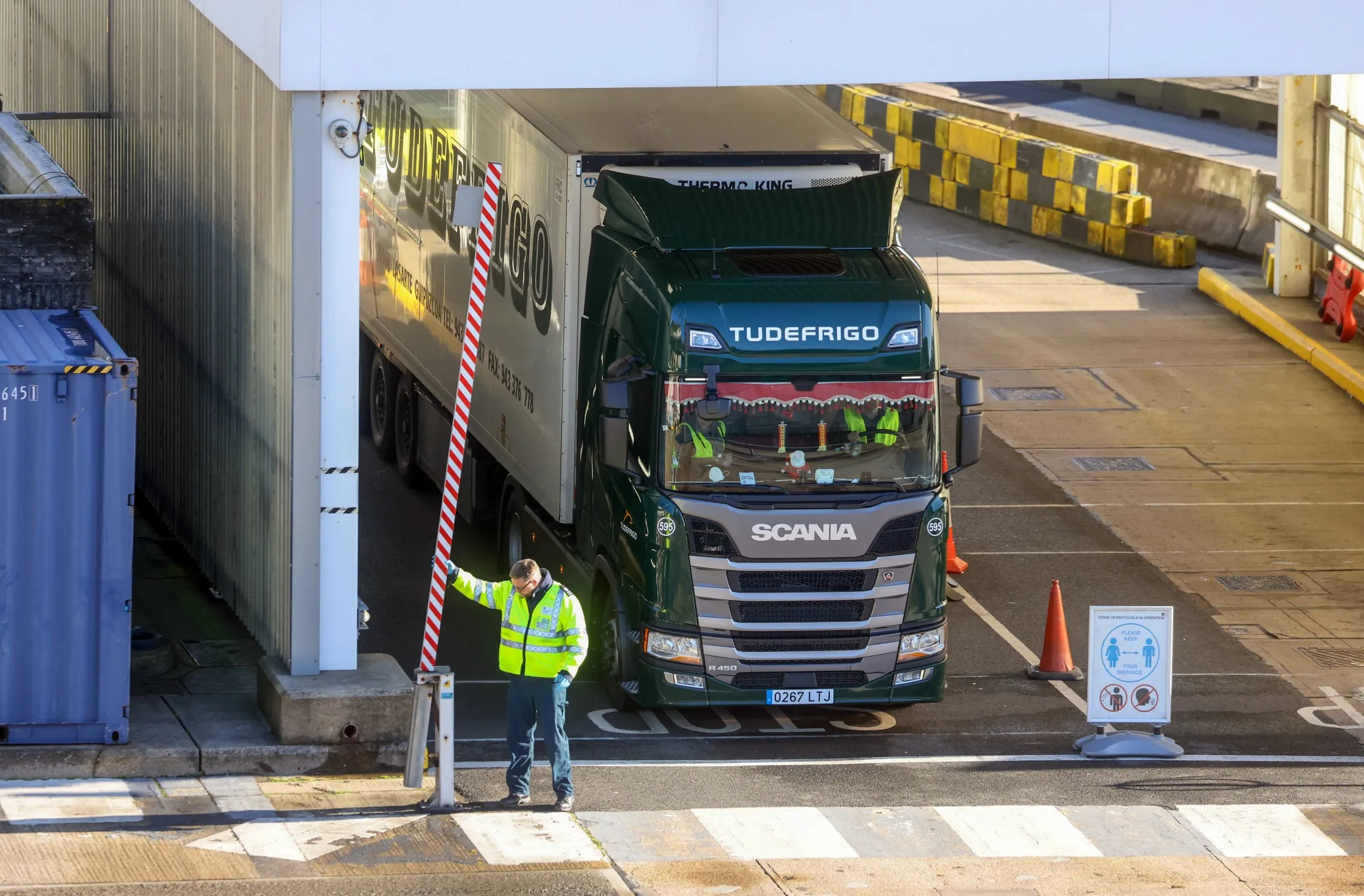 A border force police officer lifts a barrier after checking a truck in Dover, England.