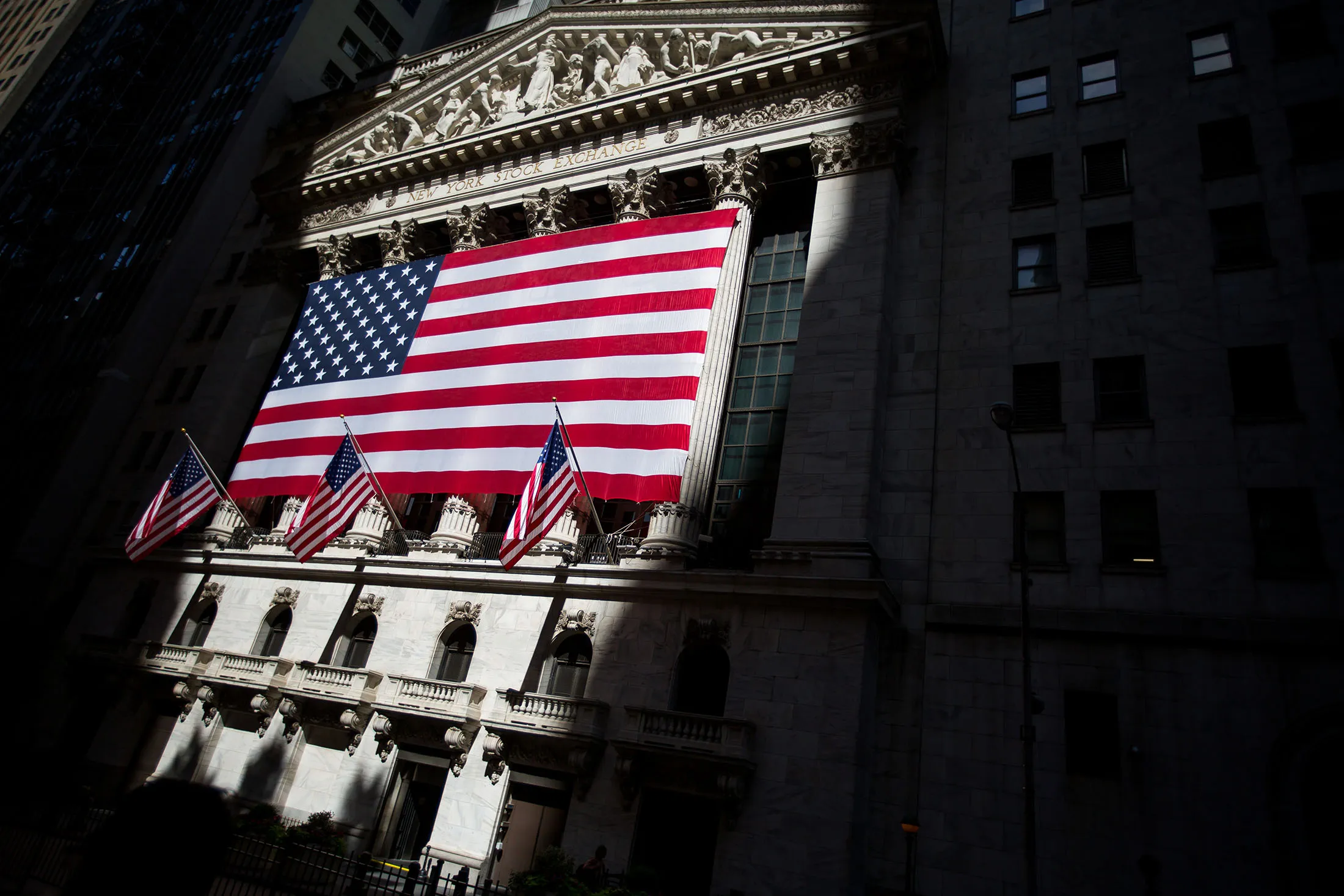 An American flag is displayed outside of the New York Stock Exchange (NYSE) in New York, U.S., on Monday, July 3, 2017. U.S. stocks rose in light trading and the dollar strengthened as factory data bolstered optimism in the strength of the American economy. Crude climbed for an eighth day.
