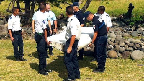 Police and gendarmes carry a piece of debris from an unidentified aircraft found in the coastal area of Saint-Andre de la Reunion, in the east of the French Indian Ocean island of La Reunion, on July 29, 2015.