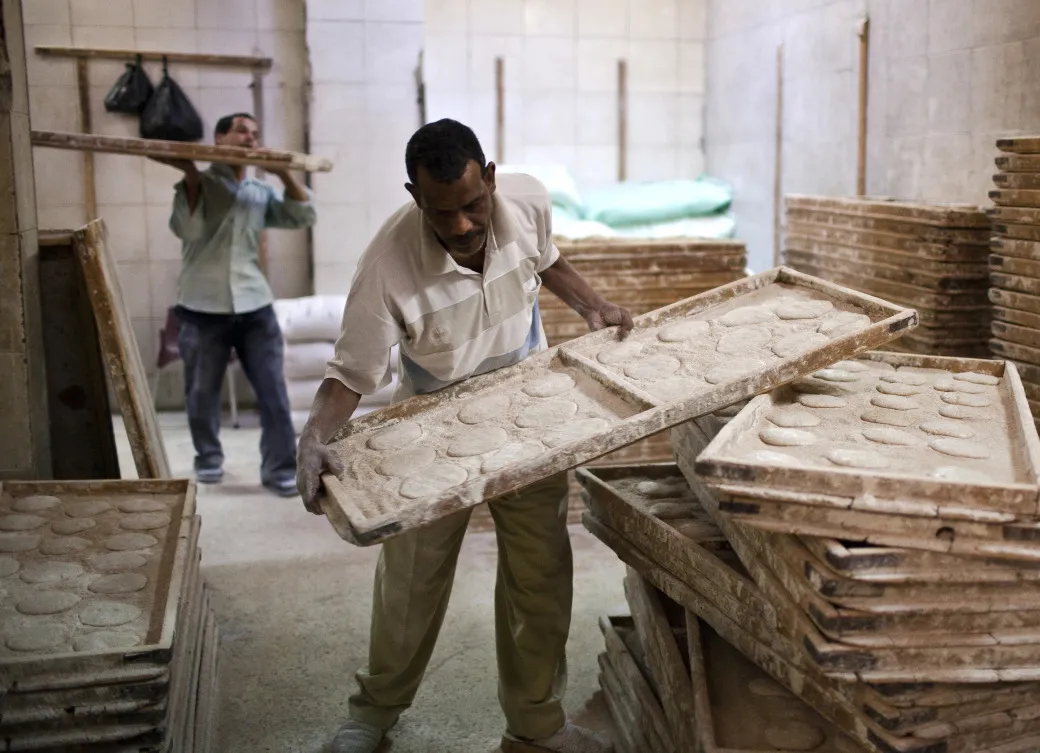Workers arrange trays of dough for baking bread in a bakery in Cairo.