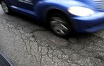 A vehicle drives over a pothole on NW 23rd Street in downtown Portland, Oregon. 