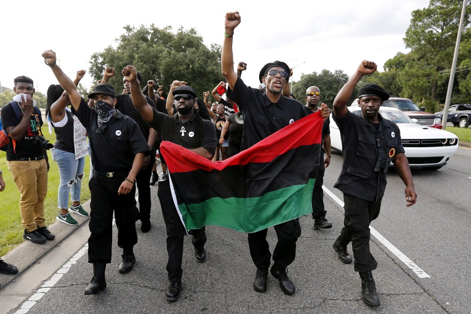 Demonstrators wearing the insignia of the New Black Panther Party protest the shooting death of Alton Sterling near the headquarters of the Baton Rouge Police Department.