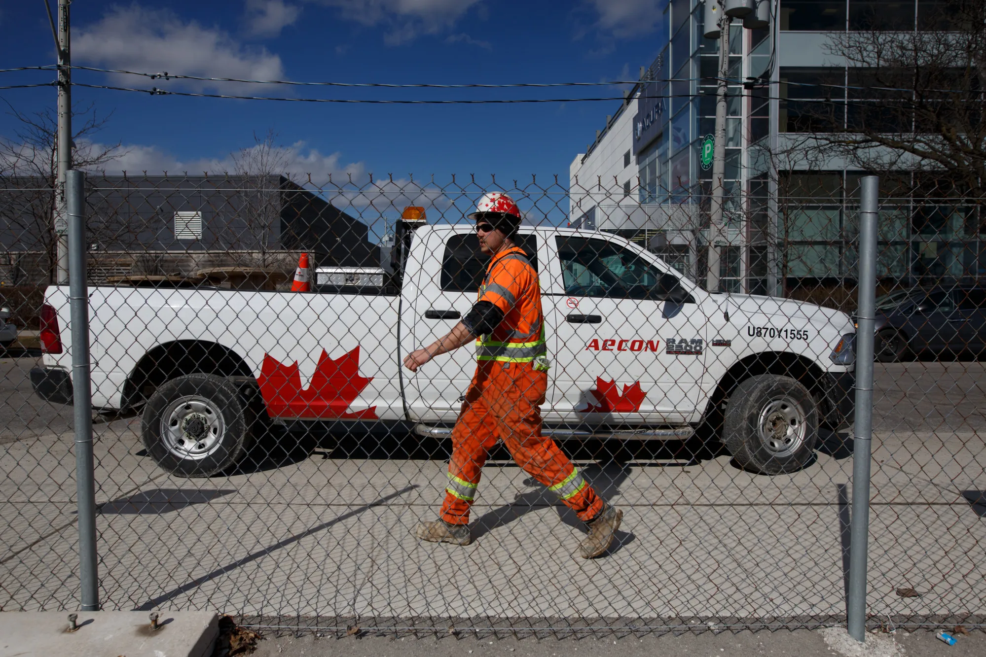 A worker passes in front of a truck displaying Aecon Group Inc. signage at a construction site in Toronto.