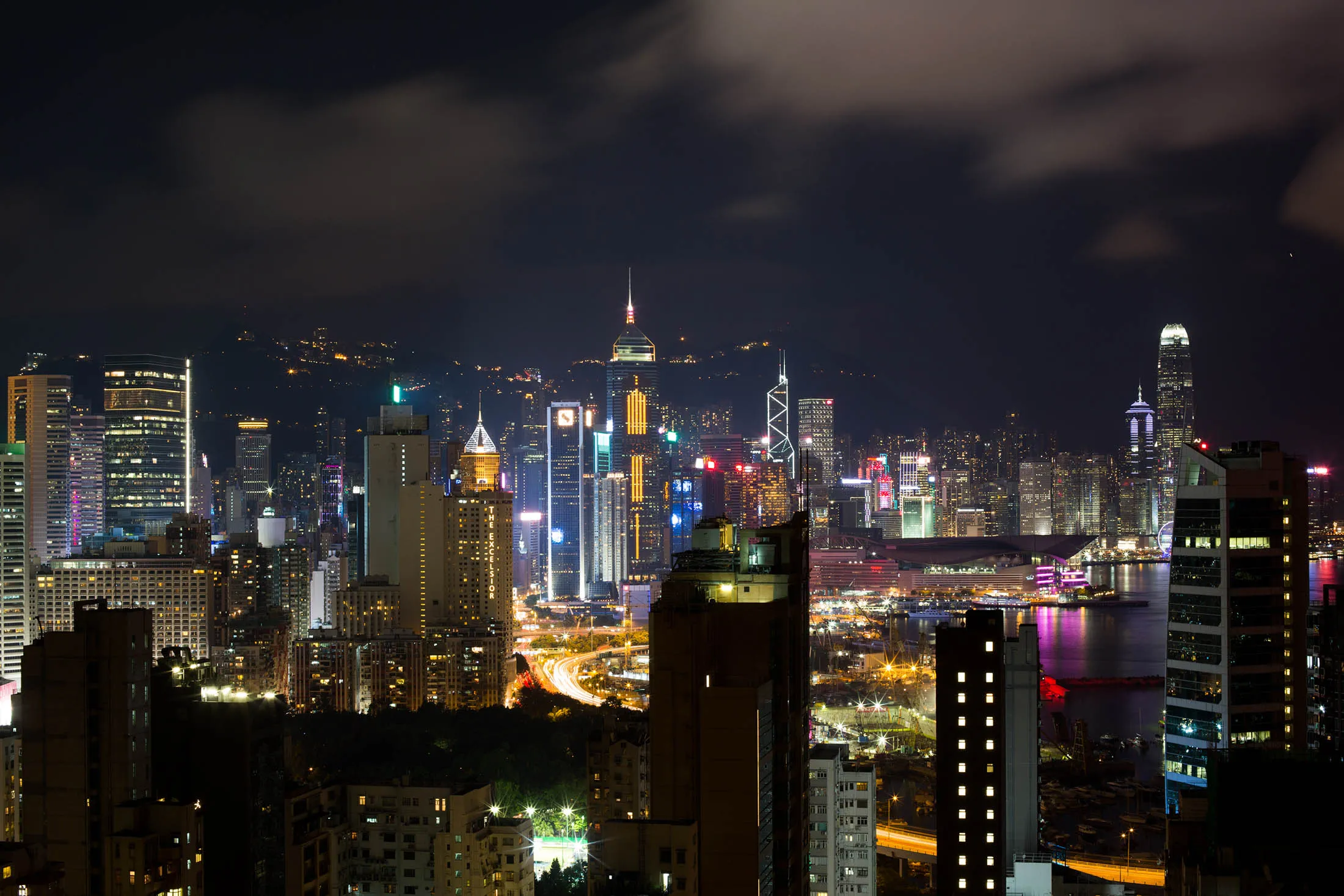 Commercial and residential buildings stand illuminated at night in Hong Kong, China, on Thursday, July 21, 2016. Hong Kong's trade balance figures are scheduled to be released on July 26.
