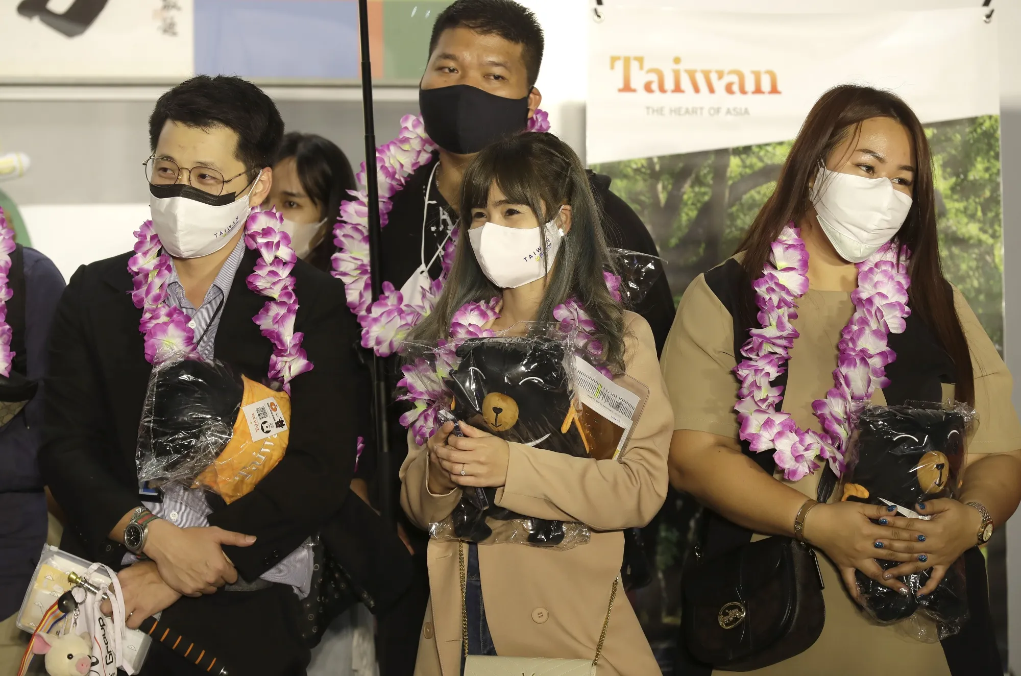 First group of foreign travelers hold souvenirs after arriving at Taoyuan International Airport in Taoyuan, Northern Taiwan, Thursday, Oct. 13, 2022. Taiwan announced that it will end mandatory COVID-19 quarantines for people arriving from overseas beginning Oct. 13. The Central Epidemic Command Center announced that the previous weeklong requirement will be replaced with a seven-day self-monitoring period.  (AP Photo/Chiang Ying-ying)