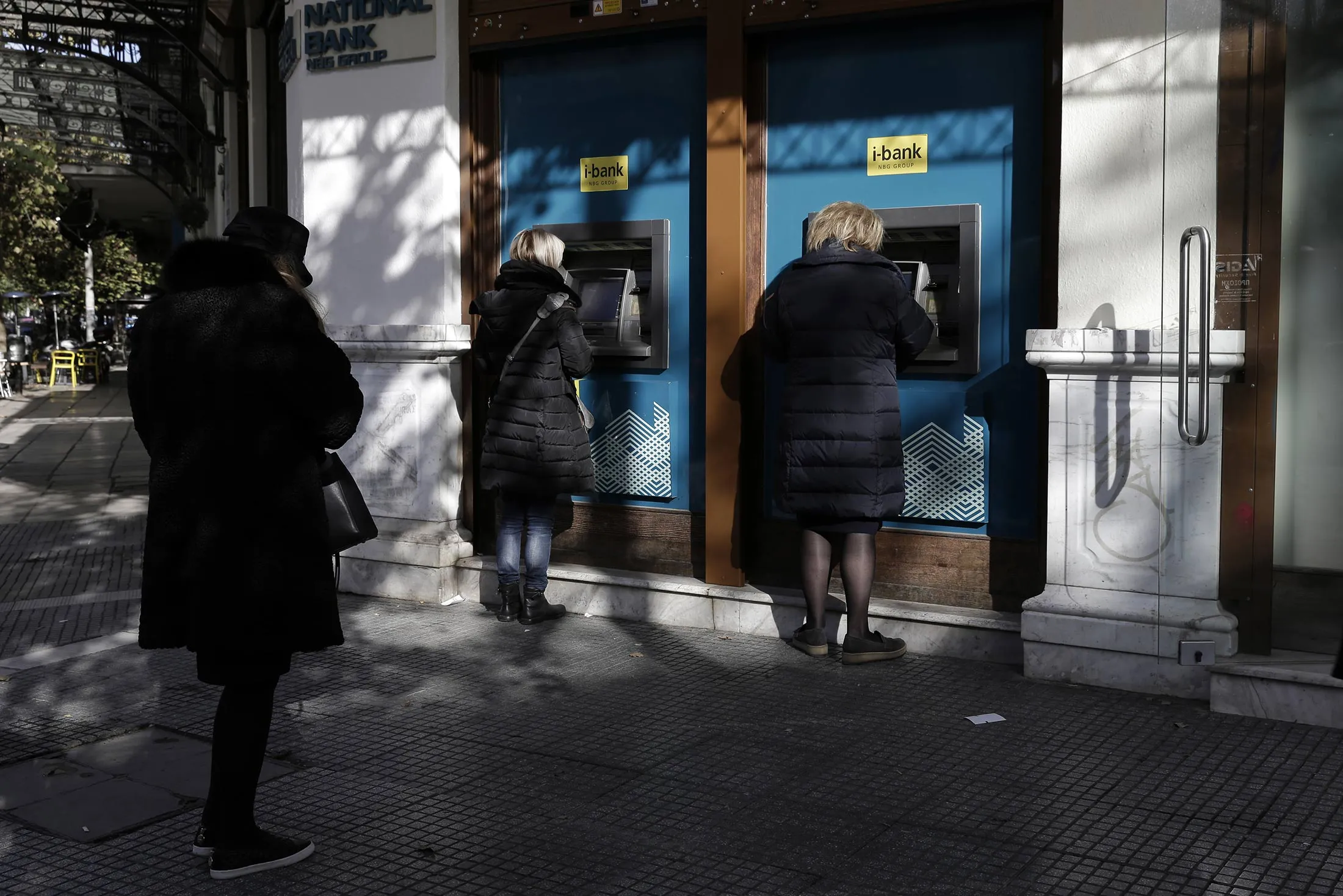 Customers withdraw cash from automated teller machines (ATM) operated by the National Bank of Greece SA in Thessaloniki, Greece, on Thursday, Dec. 1.
