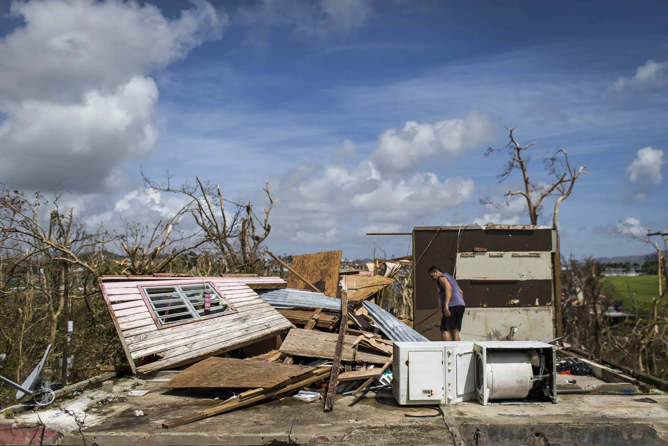 A man cleans up debris at his residence in Juncos.
