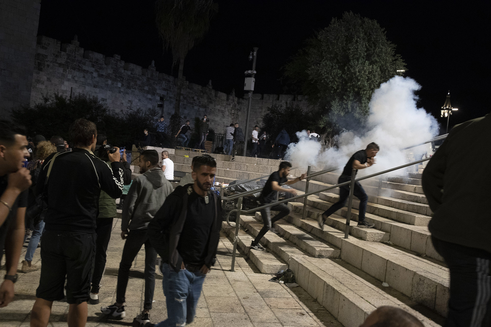 Palestinians react to stun grenades fired by Israeli police to clear the Damascus Gate after clashes at the Al-Aqsa Mosque compound, May 7.