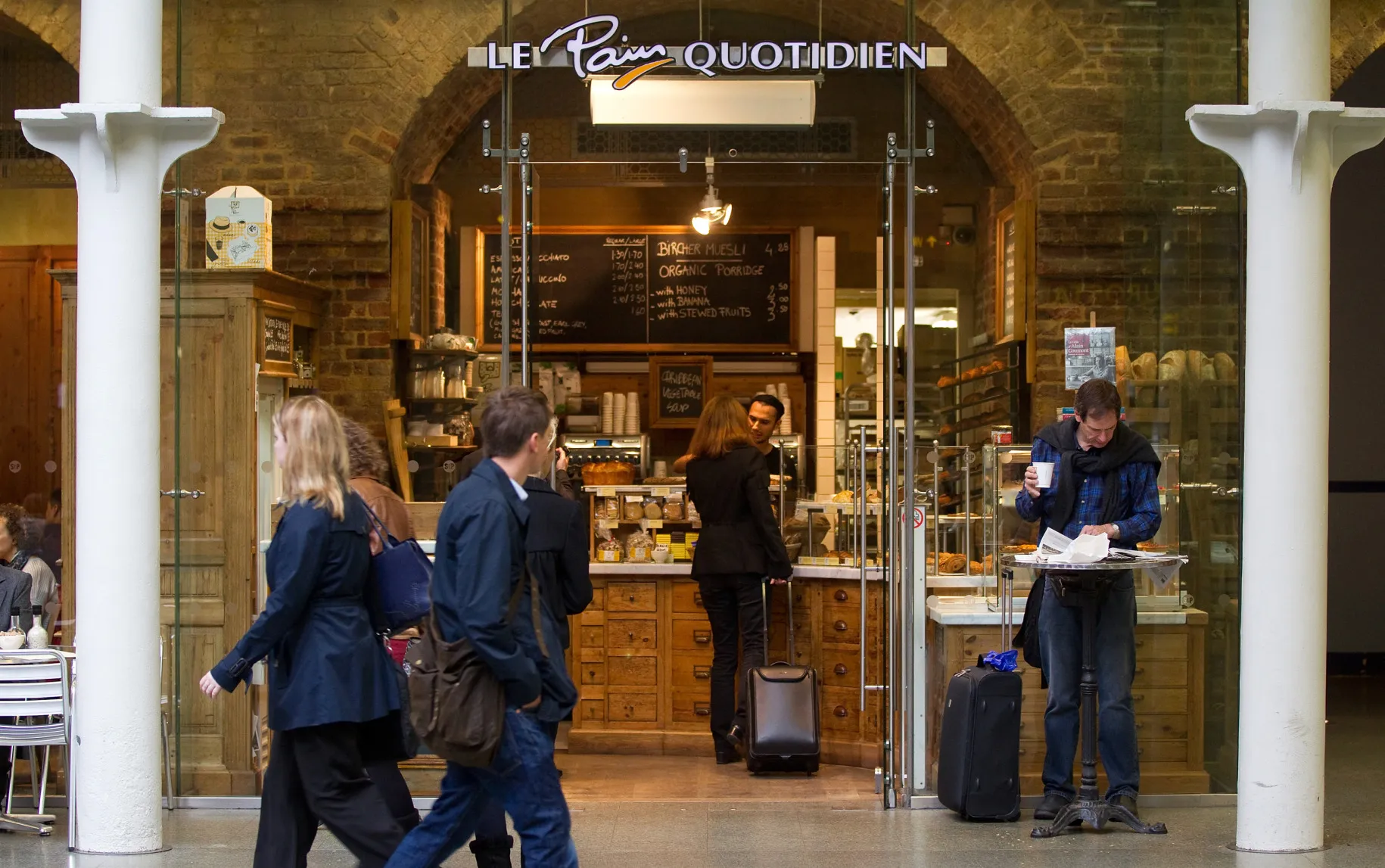 Travelers outside Le Pain Quotidien boulangerie and patisserie,at St Pancras International railway station in London, UK.