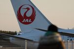 A man looks on as a Japan Airlines Co. (JAL) aircraft taxis at Narita Airport.