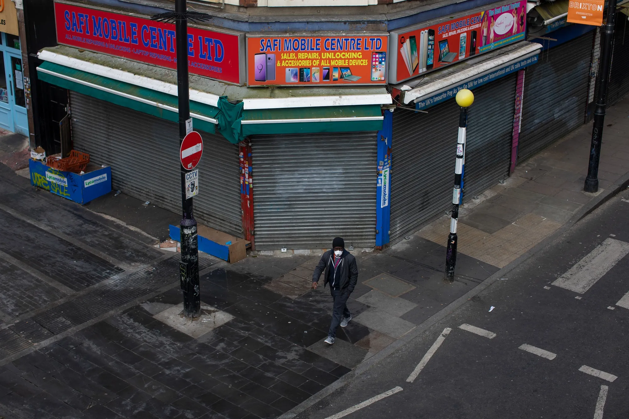A man in a protective face mask walks past a shuttered store in the Brixton district of London, April 4.