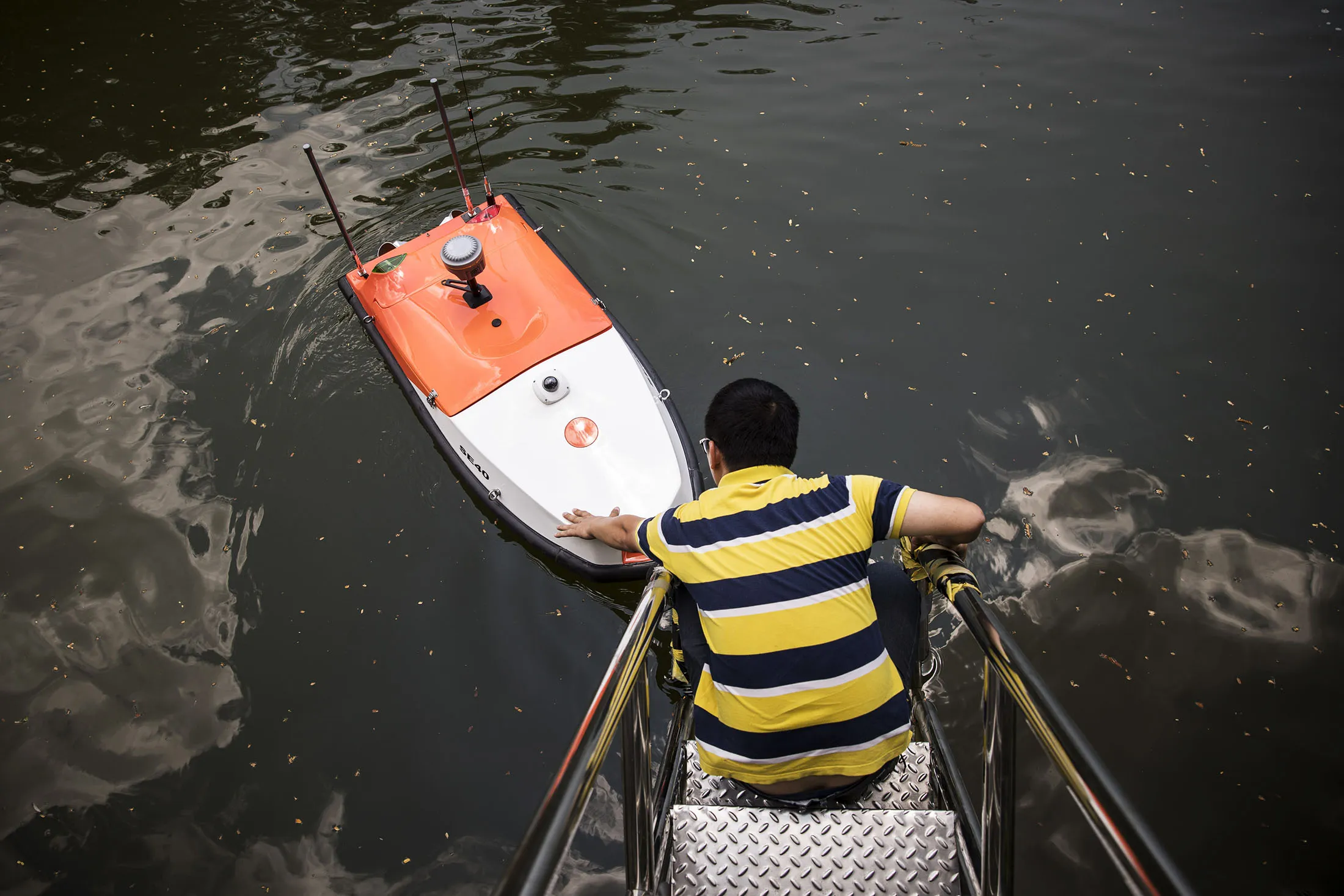 A technician inspects an Oceanalpha&nbsp;drone on a pond before a test in Zhuhai, China.