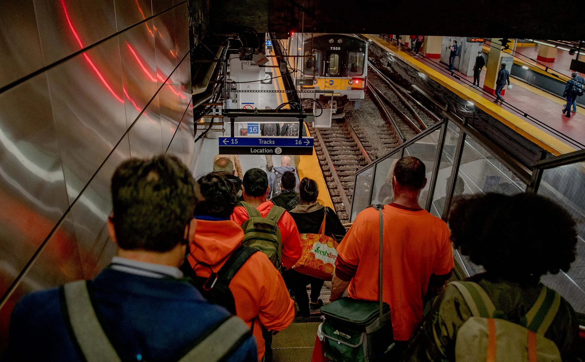 Commuters walk down stairs towards a Long Island Rail Road train at Penn Station.