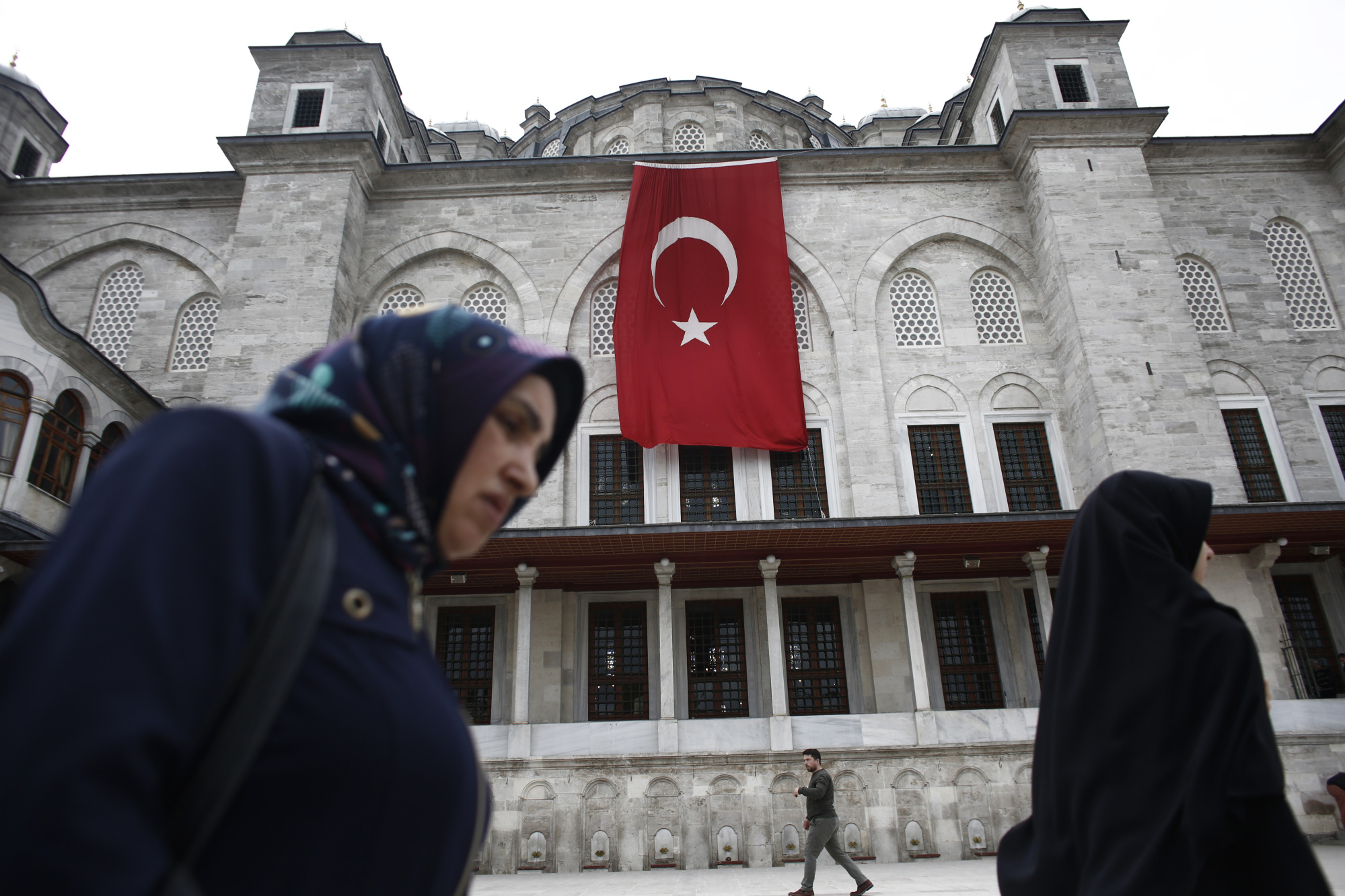 Pedestrians pass a Turkish flag hanging from the Fatih Mosque ahead of a demonstration against the relocation of the U.S. embassy to Jerusalem in Istanbul, Turkey, on Friday, May 11, 2018. No major power recognized Israeli sovereignty in Jerusalem until U.S. President Donald Trump did so on Dec. 6.