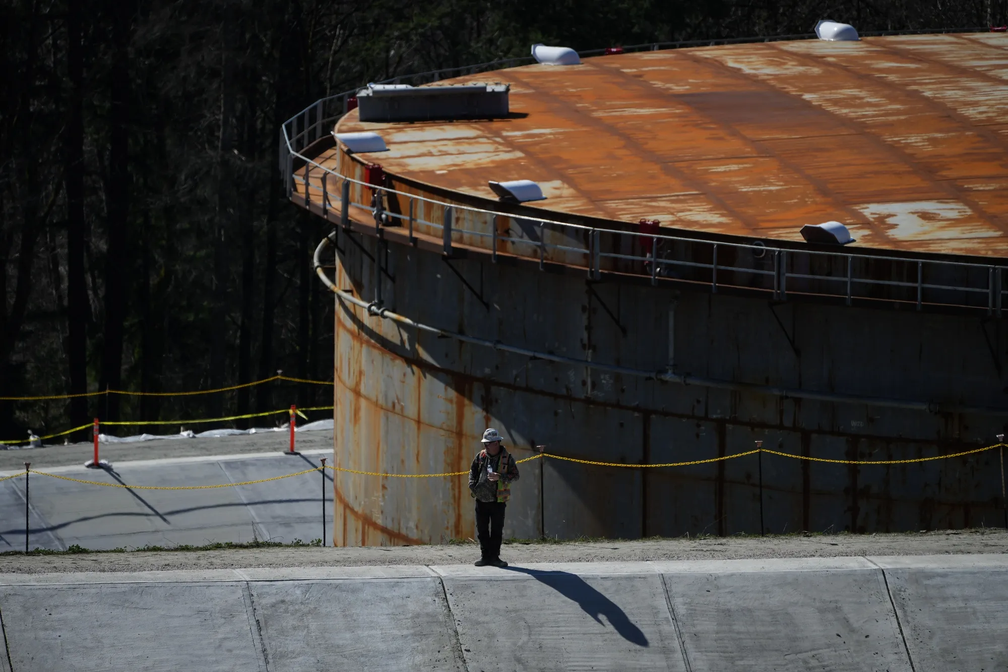 A worker stands on a concrete berm at the Trans Mountain Pipeline expansion project at the Burnaby tank farm in British Columbia.