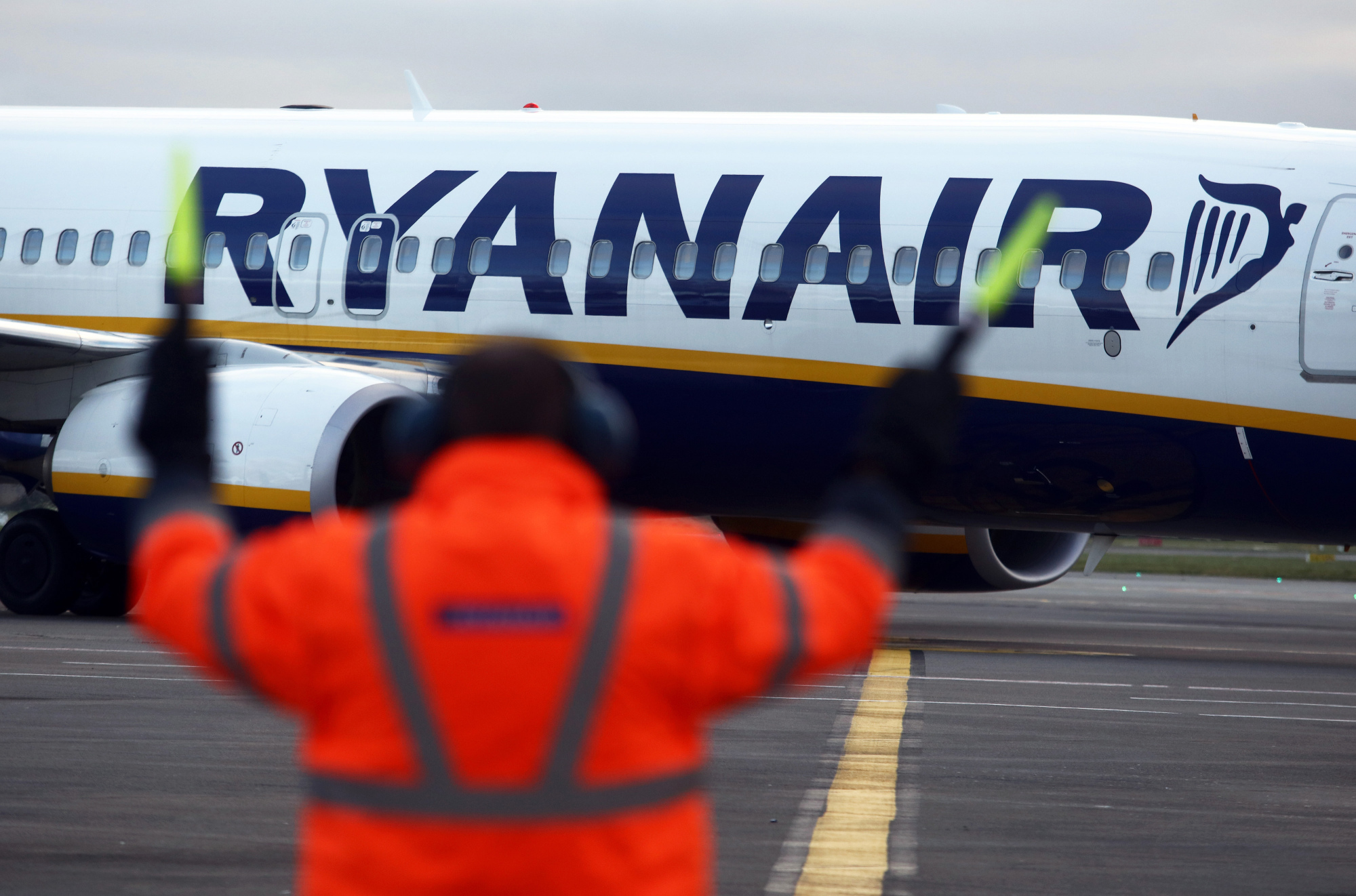 An employee uses glow sticks to guide a Ryanair Holdings Plc aircraft into position at Dublin Airport, operated by Dublin Airport Authority, in Dublin, Ireland, on Friday, Nov. 25, 2016.&nbsp;