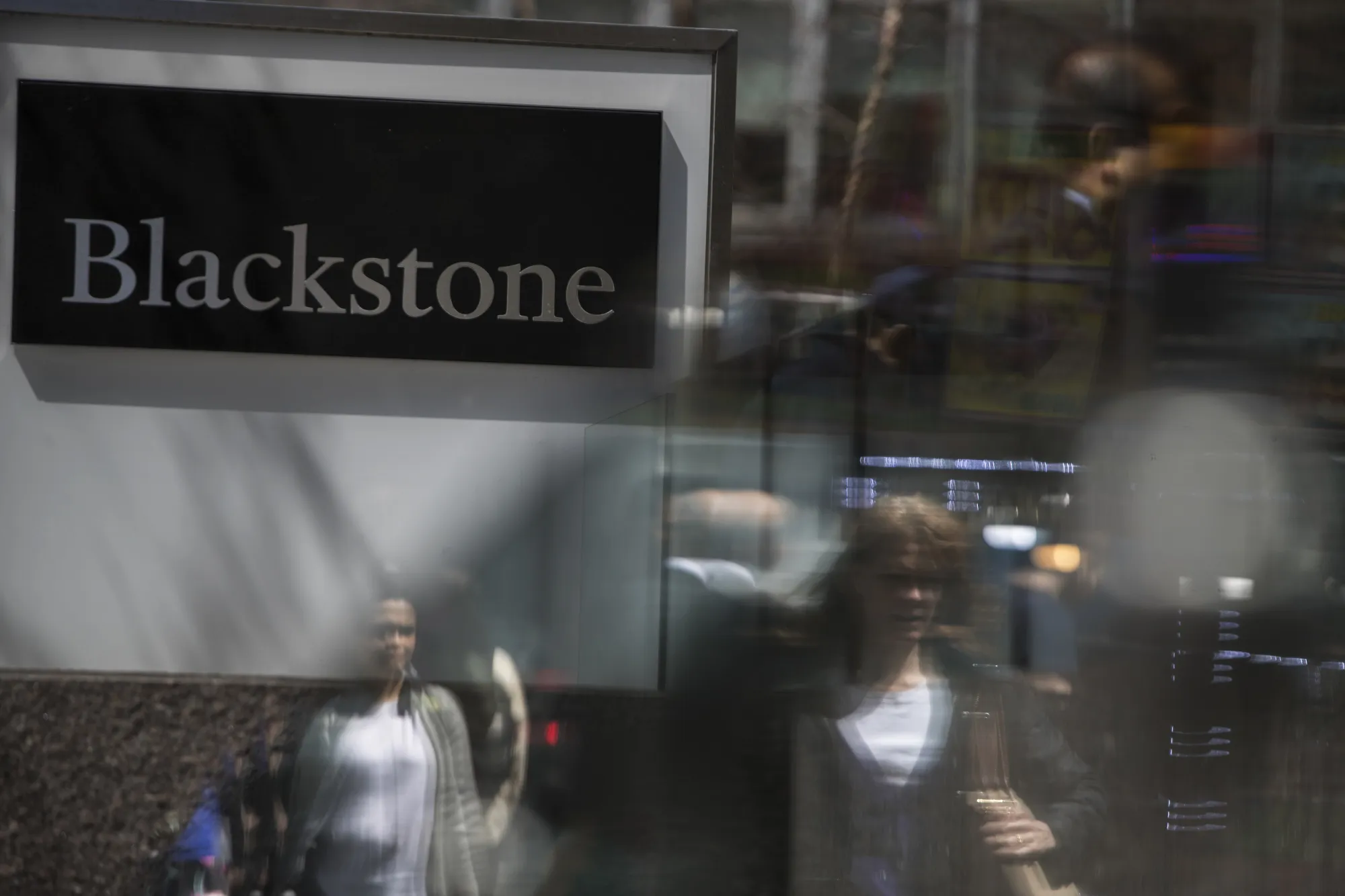 Pedestrians are reflected on glass in front of Blackstone Group LP headquarters in New York on April 14, 2017.