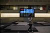 A member of the media looks at a mobile phone as he walks in front of a screen displaying share prices inside the Tokyo Stock Exchange (TSE), operated by Japan Exchange Group Inc. (JPX), in Tokyo, Japan, on Tuesday, May 7, 2019. Trading resumed Tuesday after a 10-day Golden Week holiday with a slew of news for investors to process.