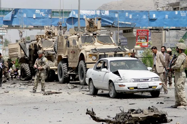 Afghan and U.S. security forces inspect the wreckage of an armored vehicle at the site of a suicide attack in Kabul on Aug. 10
