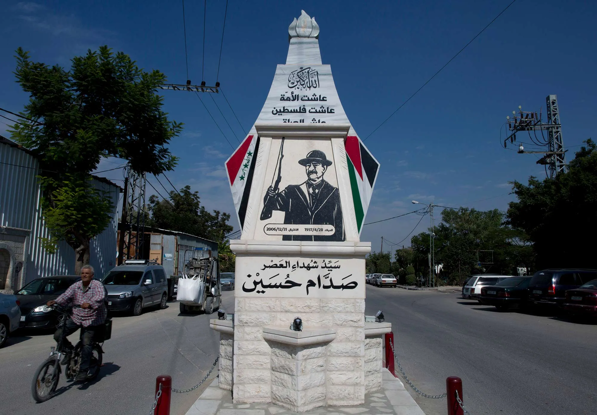 A Palestinian rides a bicycle past a monument commemorating the late Saddam Hussein in the West Bank city of Qalqiliya.
