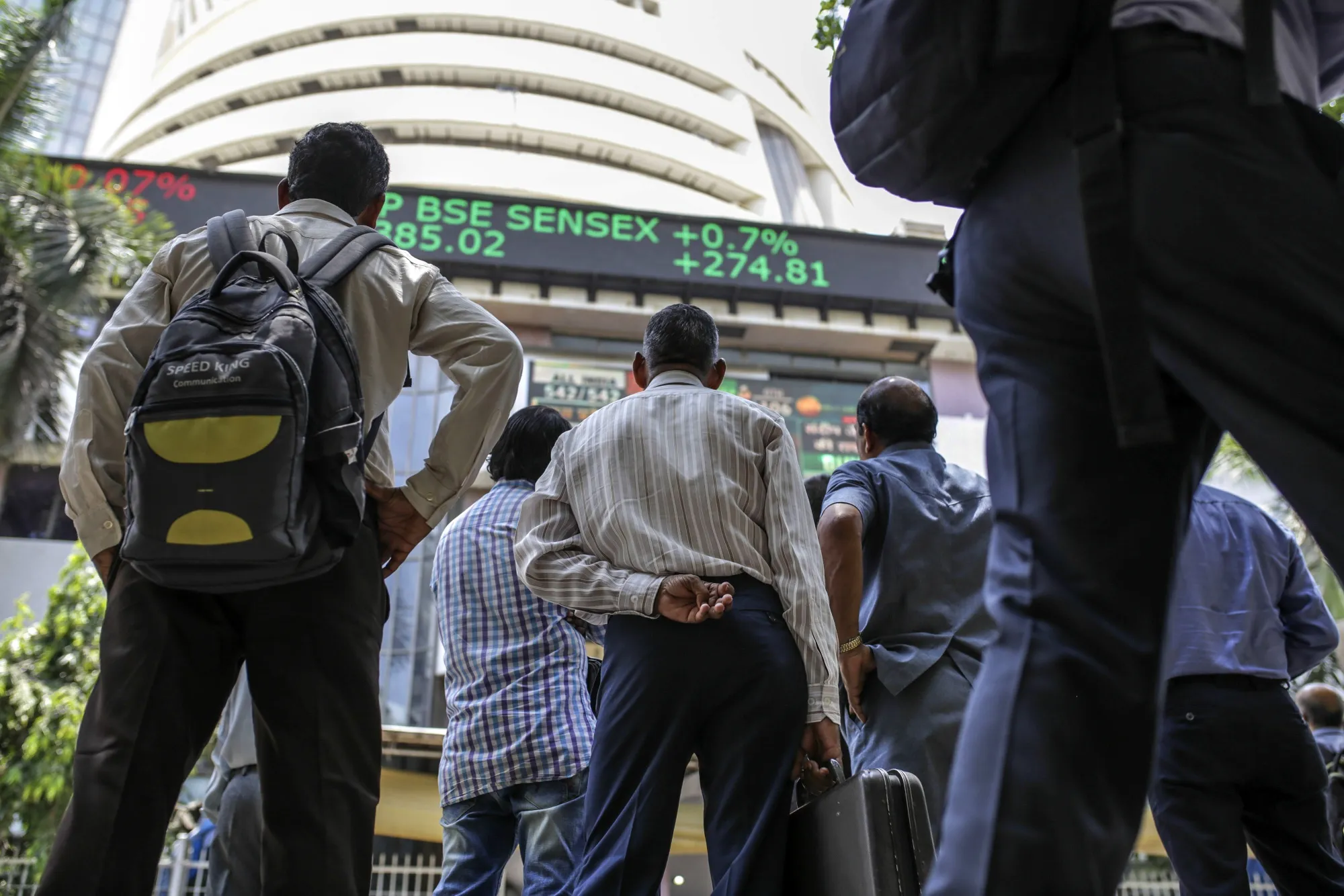 People look toward a screen and an electronic ticker board outside the Bombay Stock Exchange (BSE) building in Mumbai.