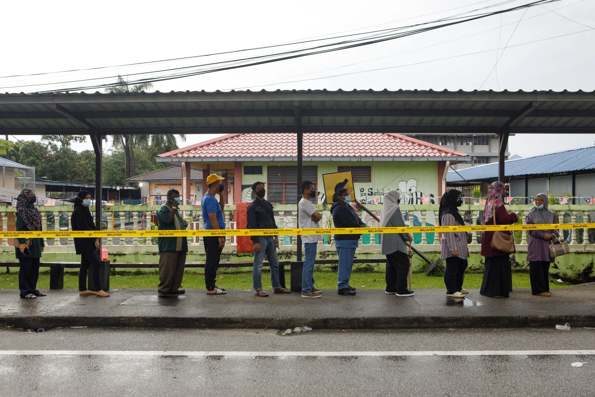 Voters stand in line outside a polling station during a general election in Shah Alam, on Nov. 19.
