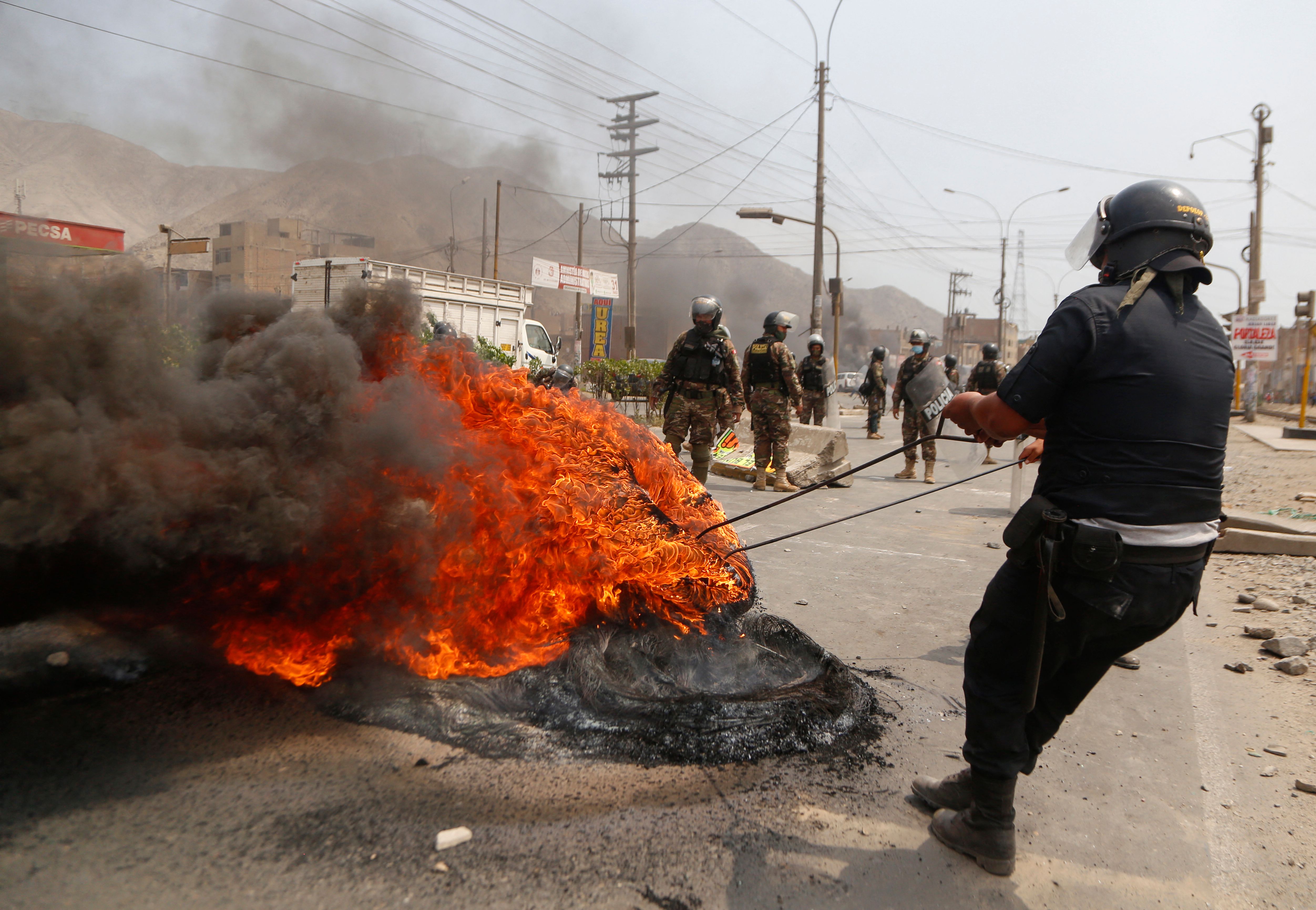 A police officer tries to extinguish a barricade set on fire during a protest in Lima on April 4.